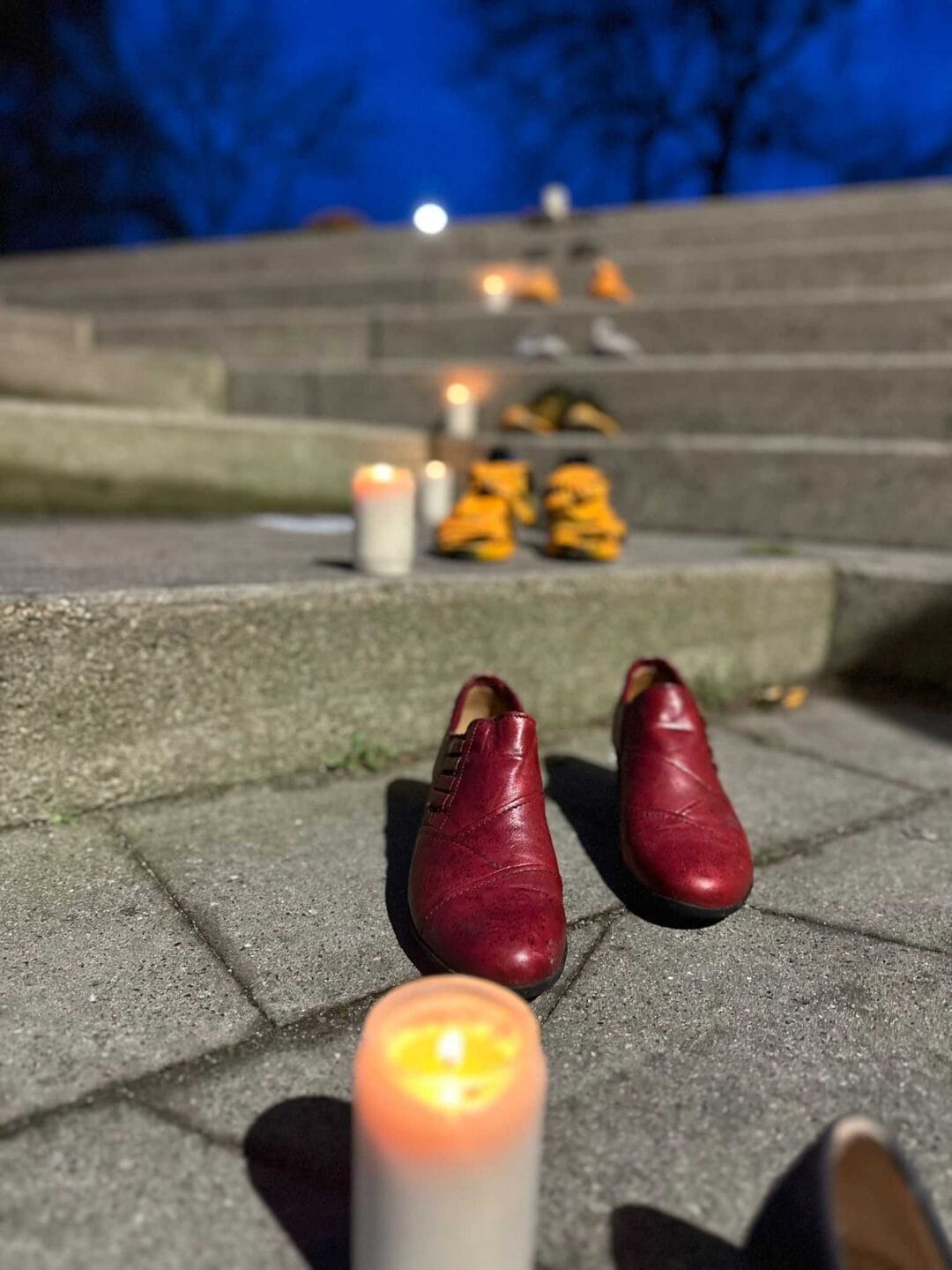 Das Bild zeigt Kerzen und Schuhpaare auf den Treppenstufen vor der Malzfabrik in Grevesmühlen (Mecklenburg-Vorpommern). Sie sind Teil einer Protestaktion.