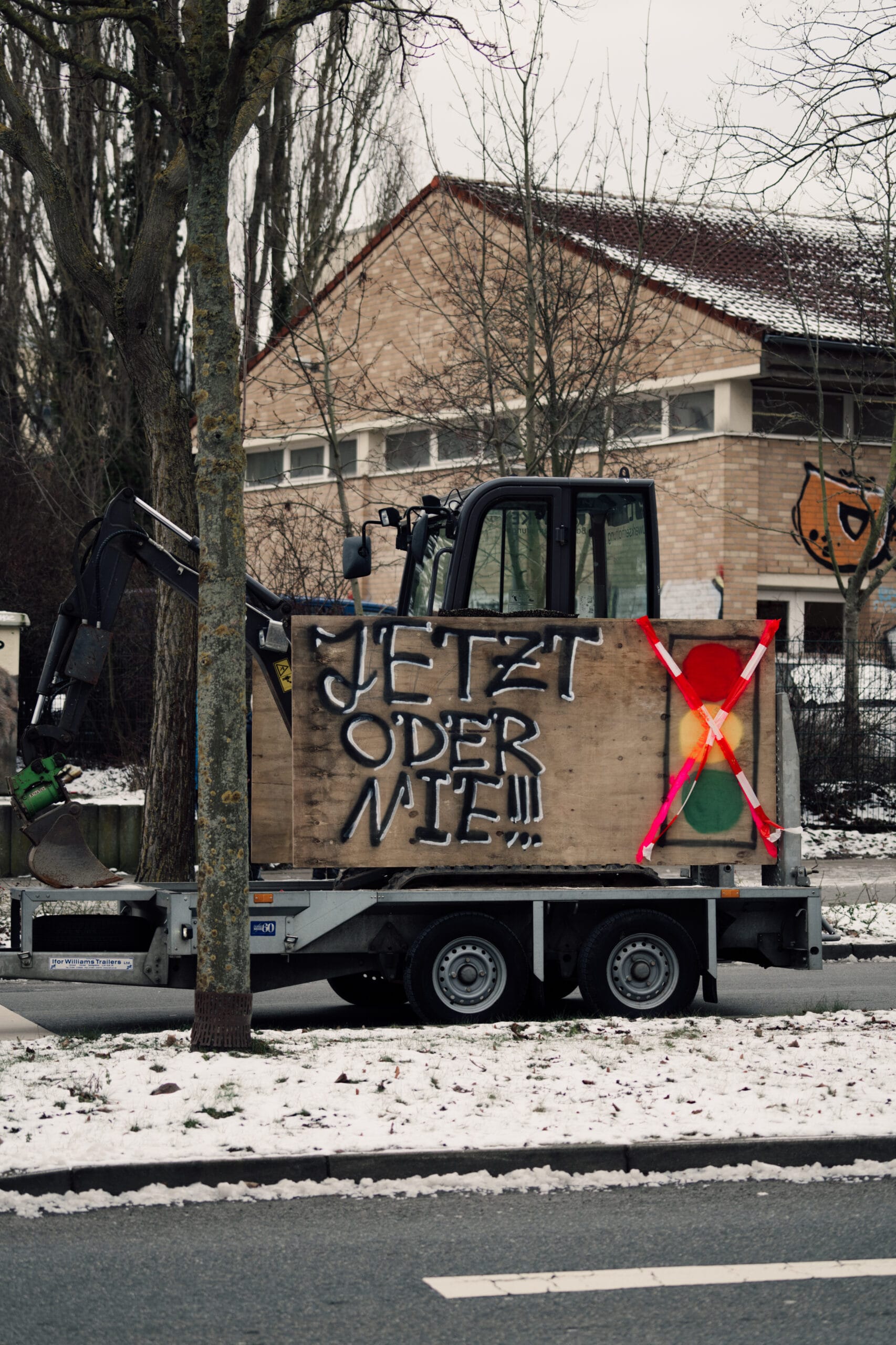 Bagger mit einem Schild, auf dem die Ampel durchgestrichen ist. Dazu steht: 