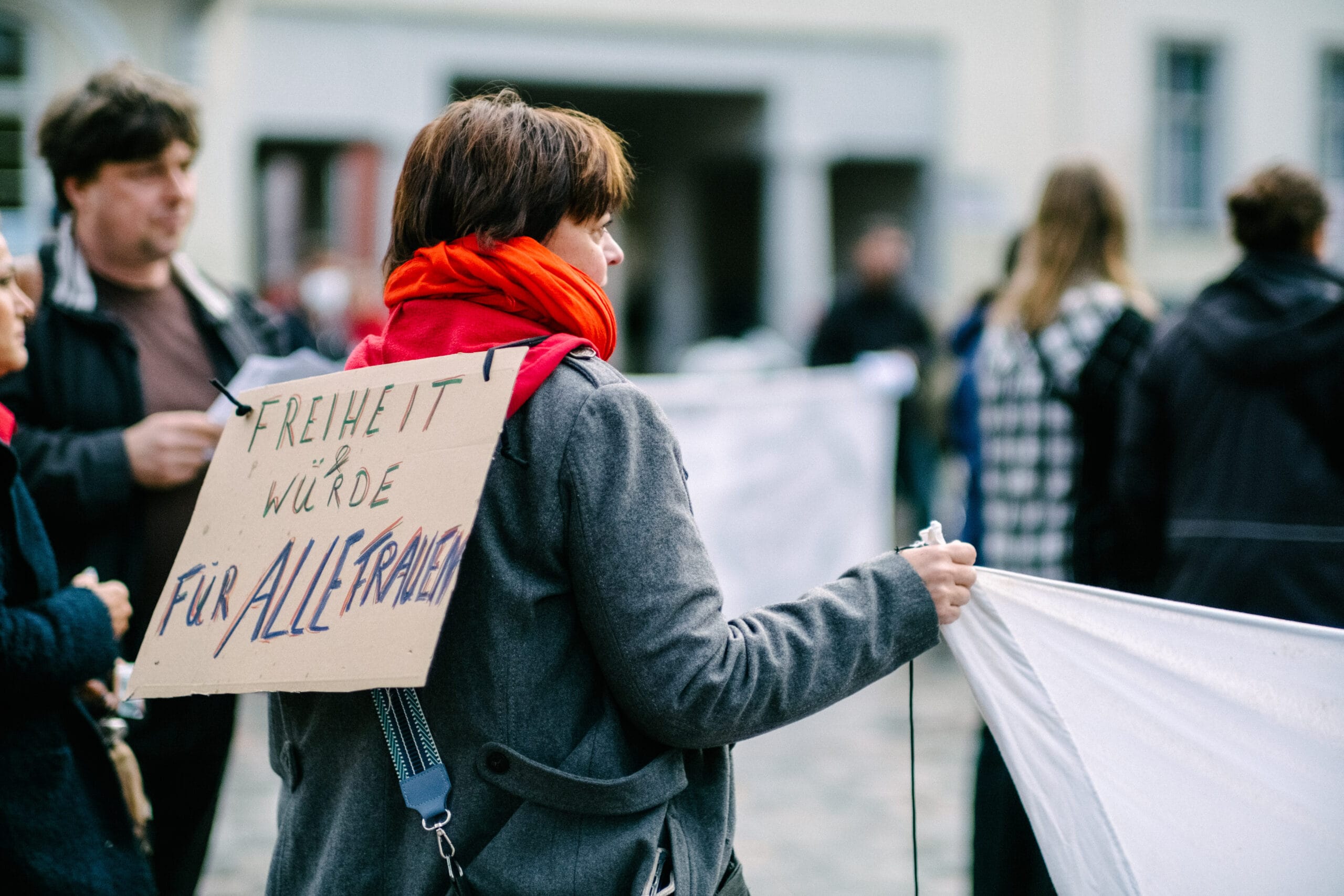 Eine Frau hat ein Schild auf dem Rücken mit der Aufschrift “Freiheit & Würde für alle Frauen”.