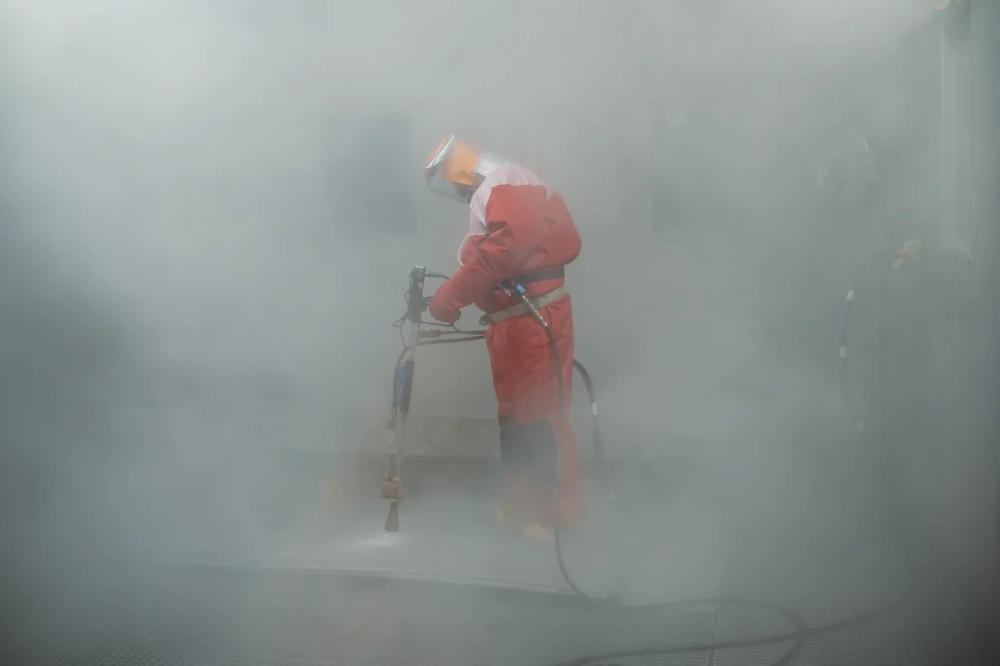 Auf dem Foto ist ein Mitarbeiter des Kernkraftwerks Lubmin (Mecklenburg-Vorpommern) zu sehen, der mit einem Hochdruckreiniger Bauteile dekontaminiert.