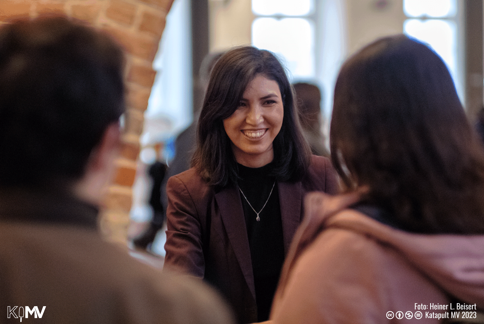 Hafiza Qasimi lächelt auf der Ausstellungseröffnung Gäste an.