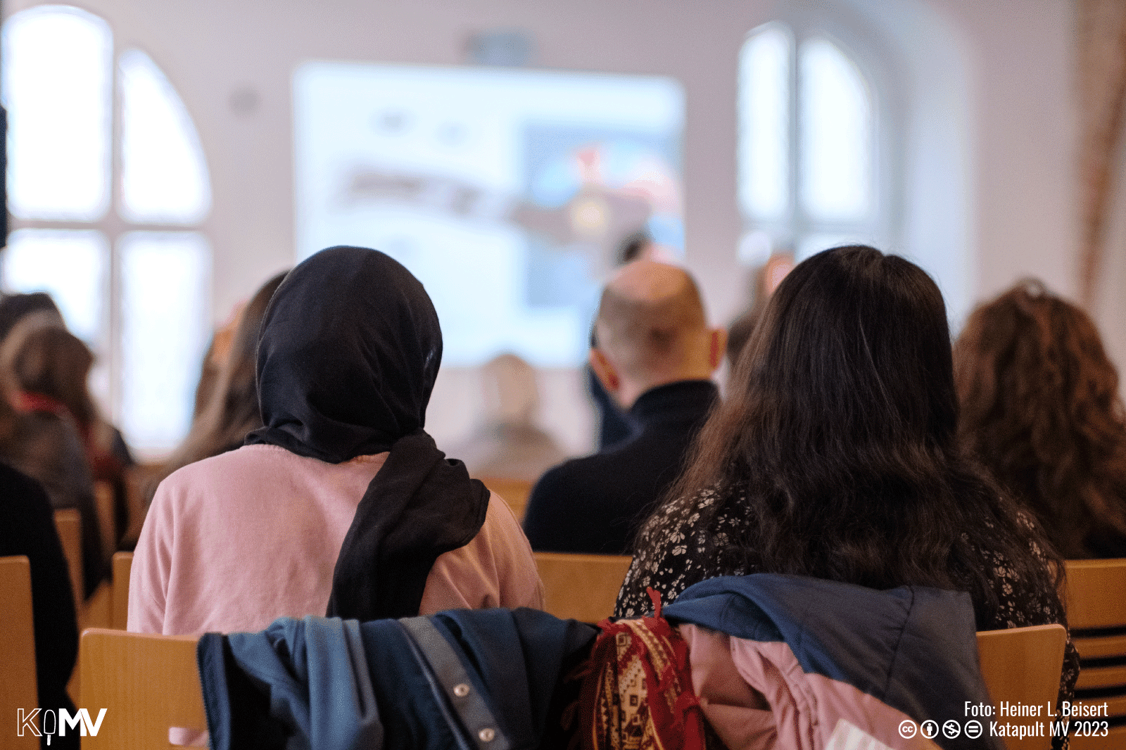 Foto vom Publikum, das auf die Leinwand schaut.