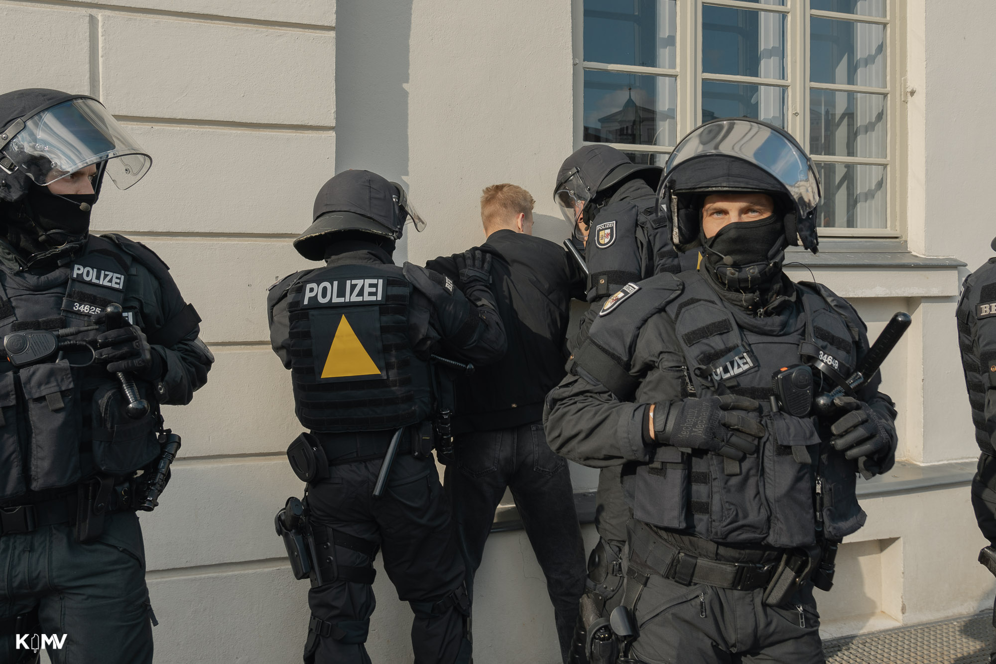 Am Ende des CSD kam es auf dem Marktplatz von Wismar (Mecklenburg-Vorpommern) zu mindestens zwei Festnahmen. Es kam zu Zusammenstößen zwischen Antifa und mutmaßlich Rechtsextremen Personen. Auf dem Bild sind fünf Polizeibeamten in Schutzkleidung zu sehen, die einen Mann an eine Hauswand drücken und festnehmen.