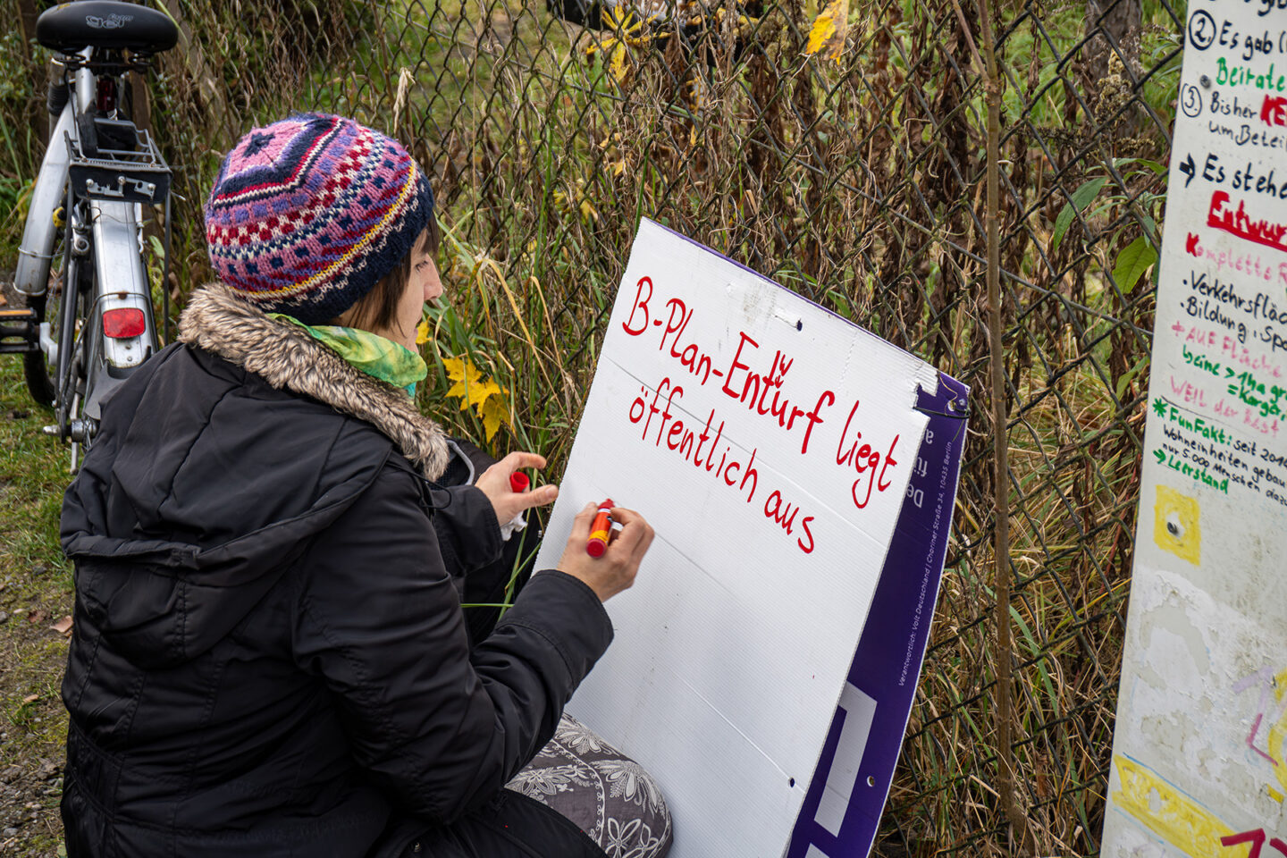 Juliane Bäthge beschriftet am Eingang der KGA Pütterweg ein Plakat, um über den zweiten Bebauungsplan und die Möglichkeit zur Stellungnahme zu informieren. (Foto: Erik Tove Zillmann)