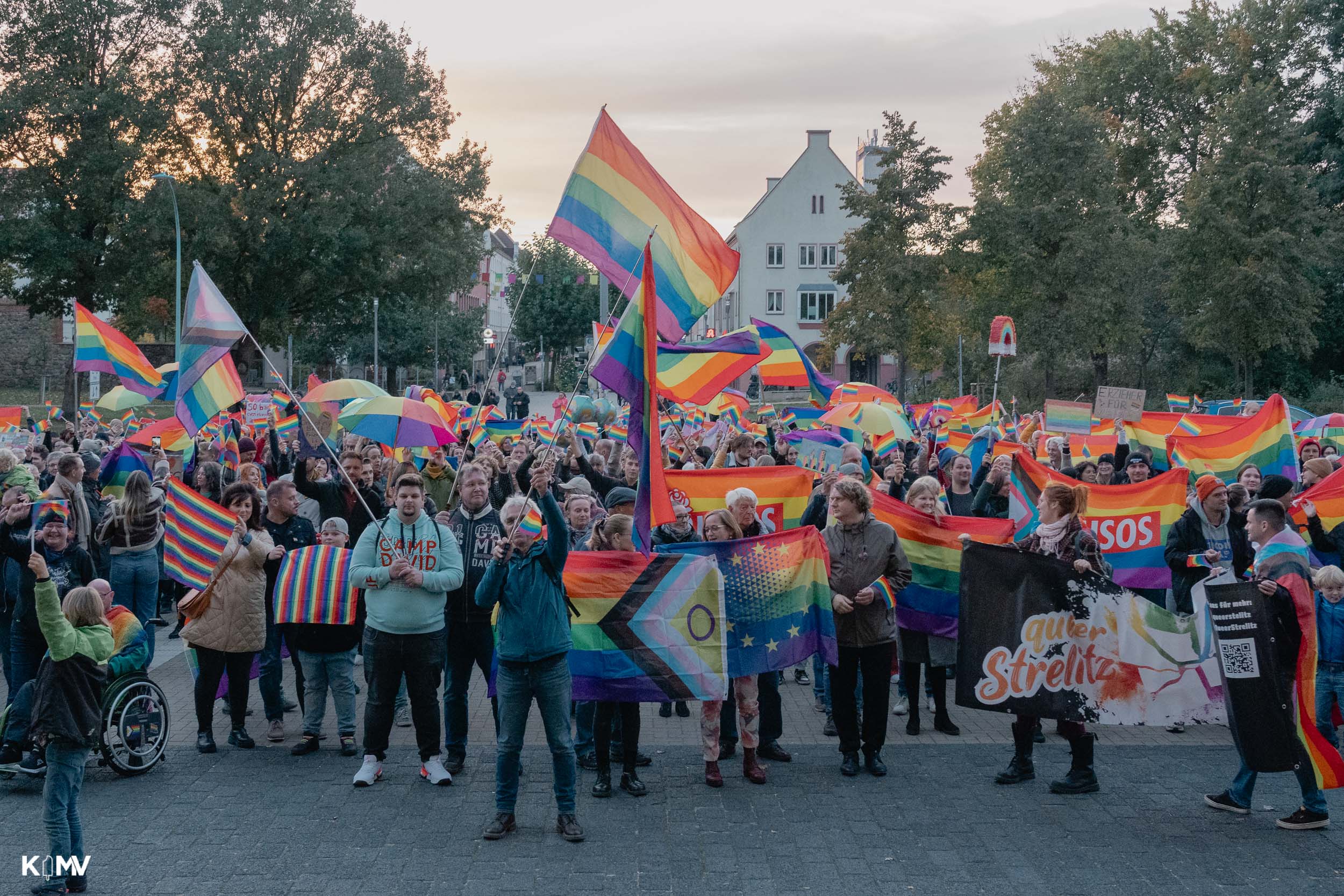 Der Rathausplatz ist voll mit Menschen. Die meisten von ihnen schwenken Regenbogenfahnen in unterschiedlichster Größe.